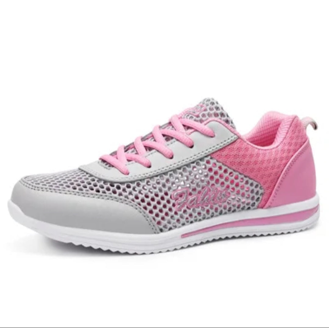 A women's athletic sneaker in gray and pink, featuring a perforated mesh upper, pink laces, a pink heel counter, and a white sole.