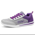 A light gray and purple athletic sneaker with a mesh upper, purple laces, and a white sole, shown from a side profile on a white background.