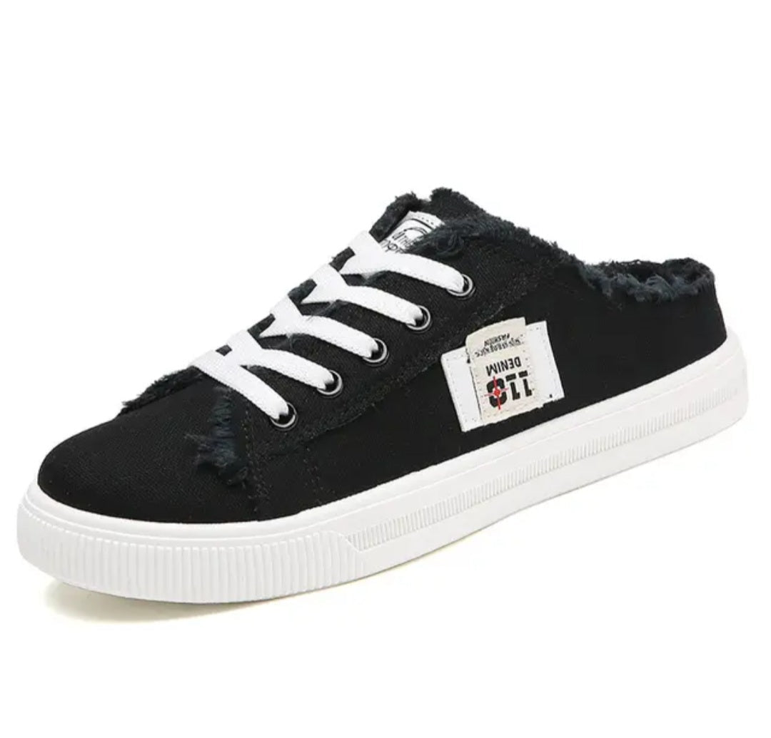 A black low-top slip-on sneaker with white laces, a white sole, and distressed frayed detailing around the collar and toe. A white side patch displays the name 'DENIM 11'.